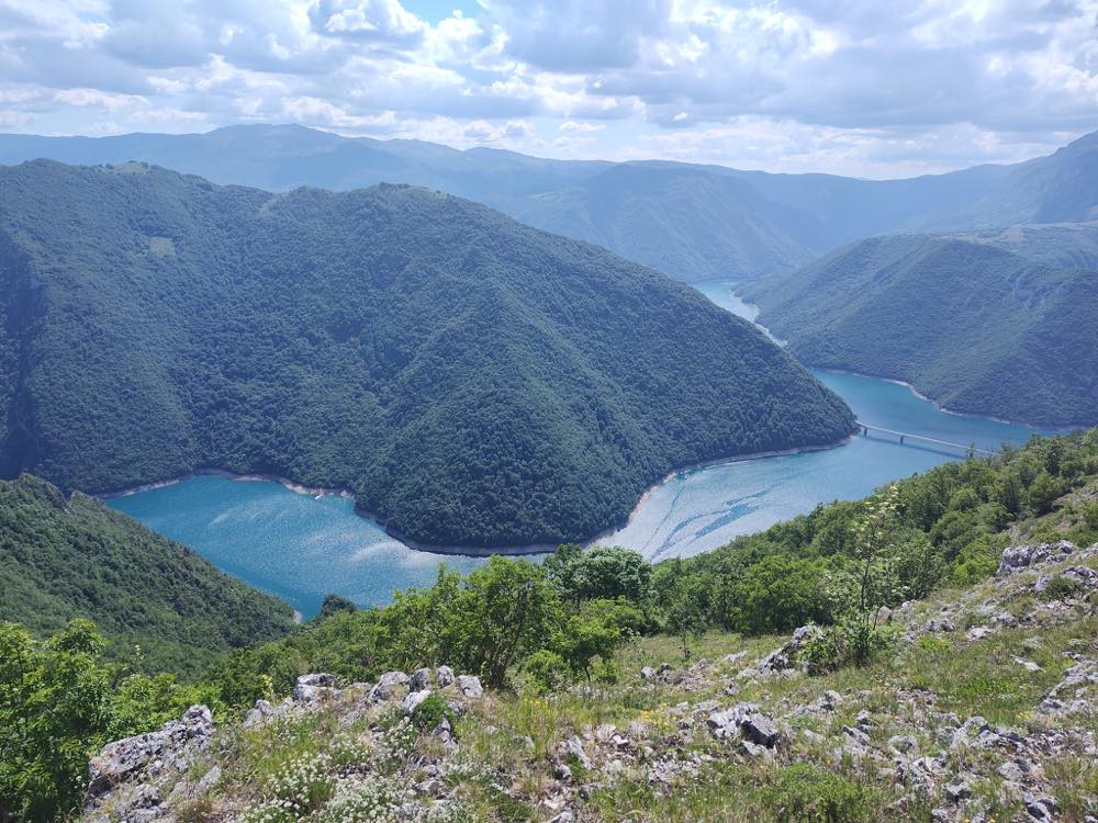 Turquoise Piva lake winding through the forested canyon